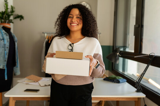 Woman holding two packages in office
