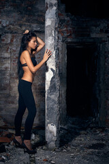 Young beautiful woman posing in ruins after fire. Full-length view of brick wall and concrete...