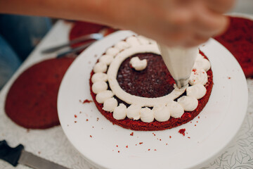 Pastry chef spreads cream and makes delicious red velvet cake. Cooking and decorating dessert.