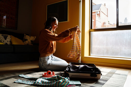 Woman putting clothes on suitcase