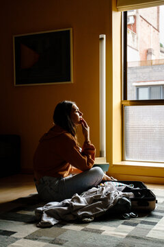 Pensive woman packing suitcase