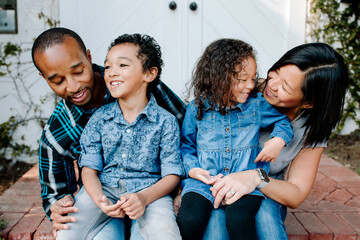 Happy mixed race family sitting on porch