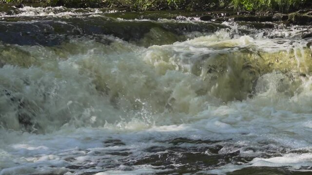 Super slow motion river water flowing over the rocks; Ocqueoc Falls, rushing water over rocks in Northwest Michigan after months of rain in late summer--late morning.  10 percent of real time. 436 10