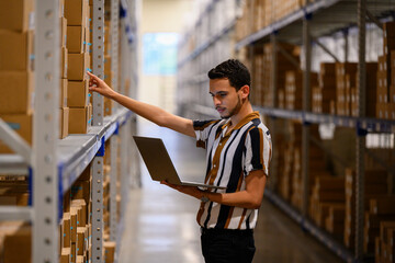 Hispanic man with laptop computer checking inventory