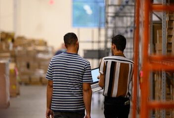 Two Workers talking  in warehouse with Laptop notebook 