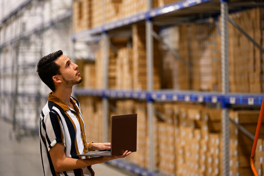 Hispanic man with laptop computer at warehouse