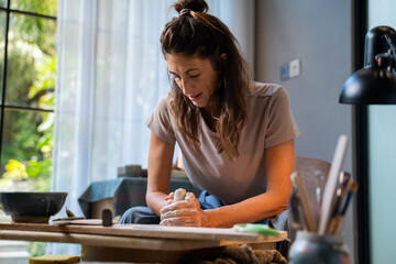 Woman focused on molding clay in hands in art studio