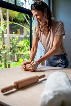 Woman preparing clay on wooden surface