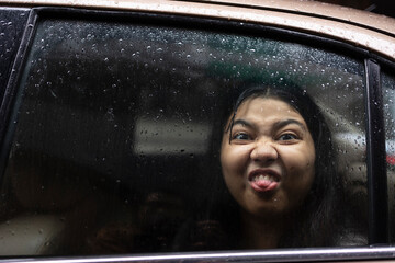 A teenage Indian girl showing tongue inside car
