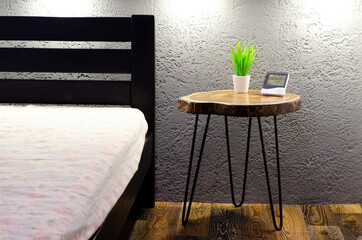 Wooden table. In the bedroom. Near the bed. Green flowerpot on the table. Interior.