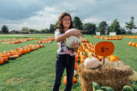 Girl proudly showing off white pumpkin. 