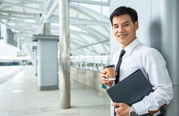 Businessman leadership hold document folder and drink cup of coffee outside near cityscape and dreaming for bigger projects with business assistants outside office. Finance portrait