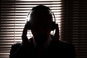 An FBI secret agent listens with headphones and records a conversation against the background of a...