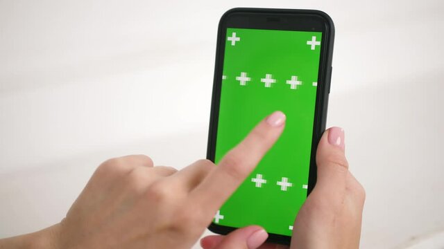 Close up shots of green screen on iphone. Lady holding in hands mobile phone device with moving interactive motion tracking points. Touching, tapping smartphone surface with fingers, sliding, swiping.