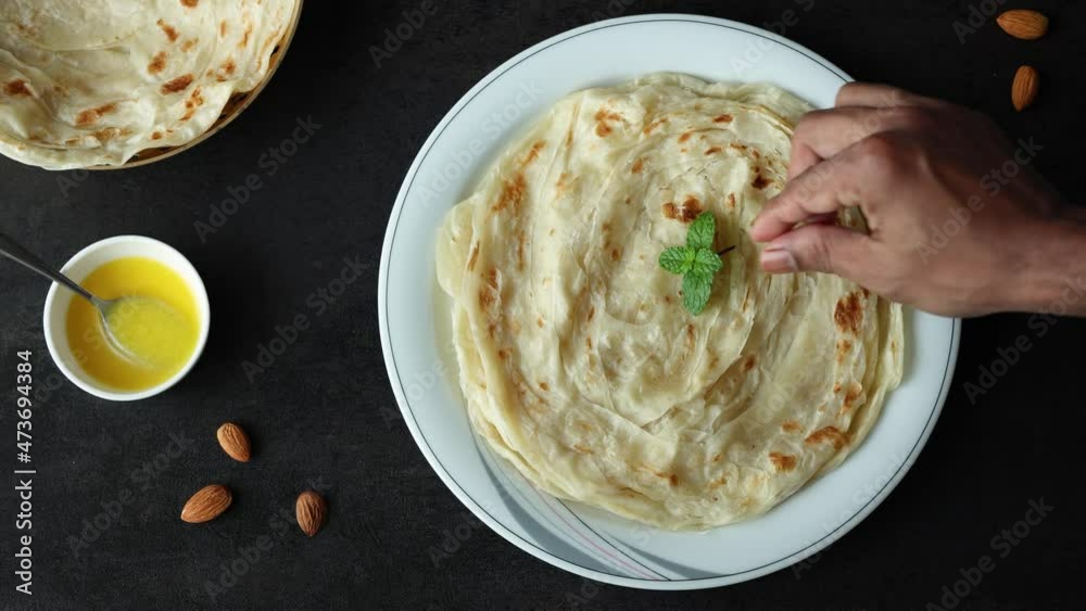 Wall mural Indian flat bread Kerala porotta woman hand serving eating Malabar porotta paratha layered bread 4K video footage whole wheat flour Maida India  chapati fulka parantha rumali roti side dish meat curry