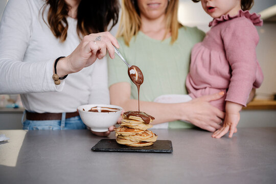 Unrecognisable mothers and daughter making pancakes