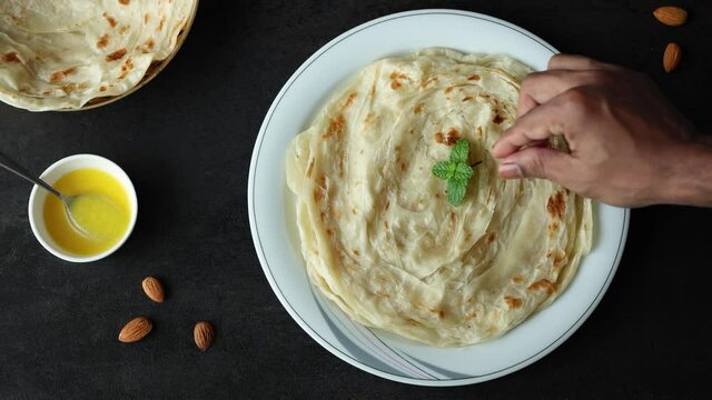 Indian flat bread Kerala porotta woman hand serving eating Malabar porotta paratha layered bread 4K video footage whole wheat flour Maida India  chapati fulka parantha rumali roti side dish meat curry