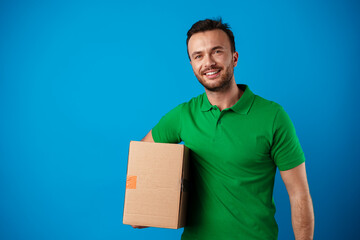 Delivery man with box in studio against blue background