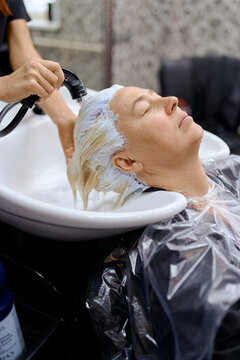 the hair master washes the client's head from hair dye