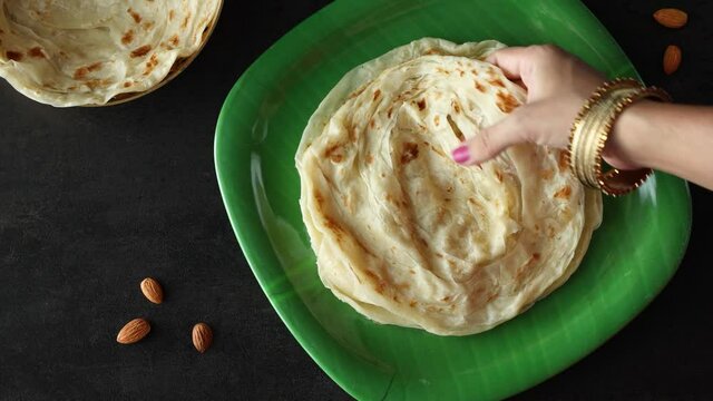 Indian flat bread Kerala porotta woman hand serving eating Malabar porotta paratha layered bread 4K video footage whole wheat flour Maida India  chapati fulka parantha rumali roti side dish meat curry