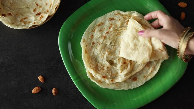 Indian flat bread Kerala porotta woman hand serving eating Malabar porotta paratha layered bread 4K video footage whole wheat flour Maida India  chapati fulka parantha rumali roti side dish meat curry