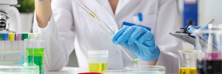 Female scientist conducts research on transparent yellow liquid in laboratory closeup