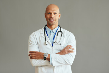 Young African American medical expert with arms crossed against background.