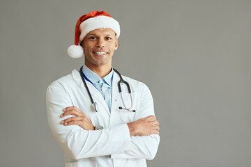 Confident African American general practitioner wears Santa hat and looks at camera.