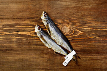 Two salted sun-dried sabrefish with paper labels on tails on wooden surface
