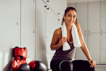 Happy sportswoman relaxes in locker room after boxing training at health club.