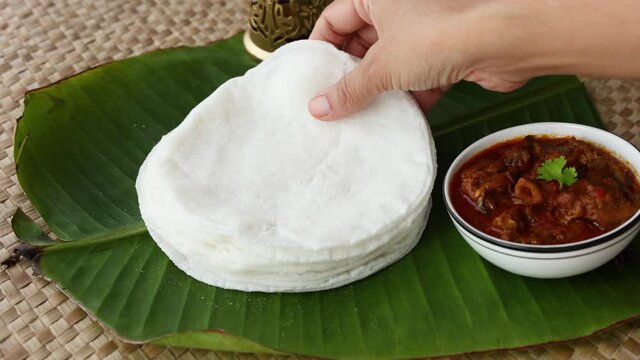 Rice Pathiri pathir flat bread spicy chicken curry woman hand serving traditional South Indian breakfast dish Rice roti 4K video footage Malabar Ramadan Ramzan, Eid festival Kerala India SriLanka