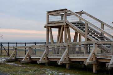 Fototapeta na wymiar platform of a lookout tower made of oak logs and planks with barrier-free access for seniors and the immobile. wheelchair ramp. metal railings of stainless steel polished tube