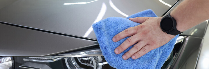 Man hand cleaning car and drying vehicle with microfiber cloth closeup