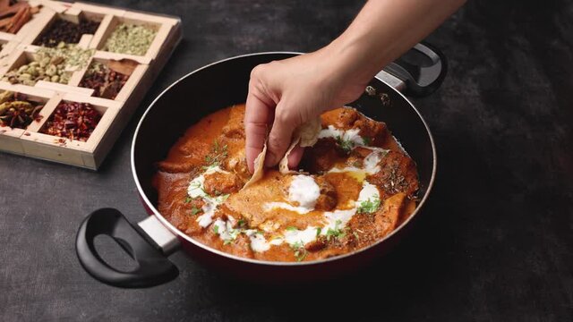 Butter chicken woman hand serving eating roti and Murgh Makhani curry roast Vindaloo hot spicy dish 4K video footage Dhaba Punjab India North Indian non vegetarian cuisine tikka Masala Chicken curry 