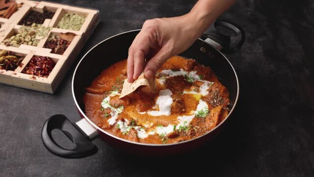 Butter chicken woman hand serving eating roti and Murgh Makhani curry roast Vindaloo hot spicy dish 4K video footage Dhaba Punjab India North Indian non vegetarian cuisine tikka Masala Chicken curry 