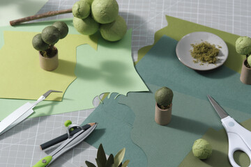 The cutting mat is surrounded by paper flowers, paper, tools 