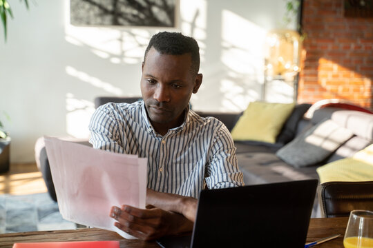 Man Using Computer And Reading Documents