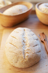 Preparations of sourdough Bread in rasstoechnye rattan baskets are on the table . The girl makes incisions with a knife and puts it in the oven to bake.