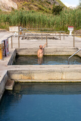 Middle-aged man bathing in a thermal spring with hot, healthy, mineral waters.