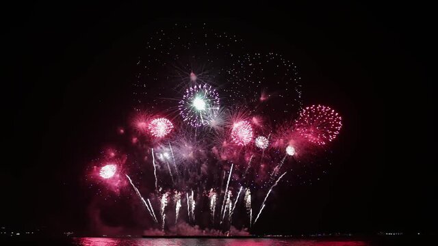 Festive beautiful colorful fireworks display on the sea beach, Amazing holiday fireworks party or any celebration event in the dark sky , Family sitting on the beach looking at fireworks