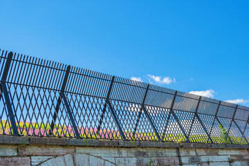 Iron fence on a wall at a blue sky