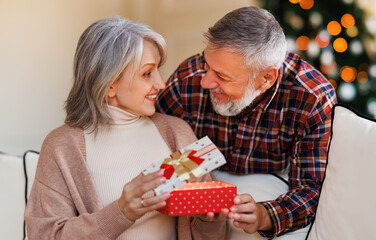Loving senior man husband giving Christmas present gift box to happy surprised wife