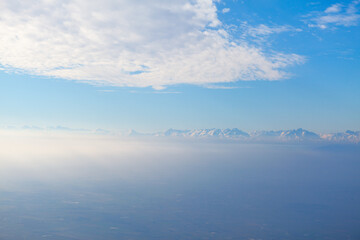 Clouds over the mountains in the haze . Snowy mountains at horizon 