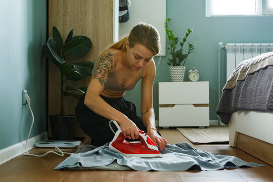 Woman ironing clothes in bedroom
