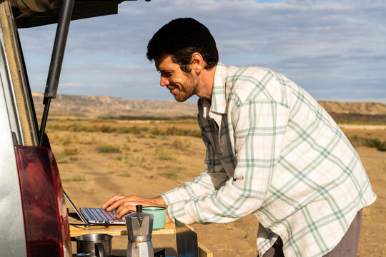 Man working on laptop in the back of a van in desert