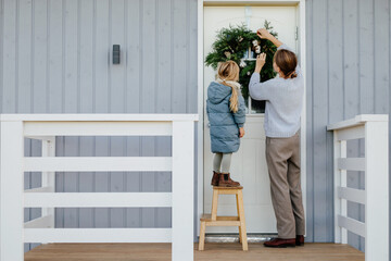 Mother and daughter hanging Christmas wreath