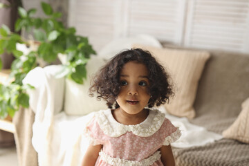 a dark-skinned girl is sitting on a wooden chair at home. the concept of environmental friendliness and children's goods. high-quality photography