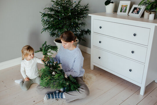Child helping mother making Christmas wreath