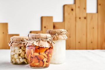 Various canned autumn vegetables in glass jars. Marinated mushrooms, garlic, champignon, onion,...