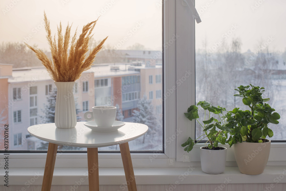 Poster cup of coffee on white table by window on winter